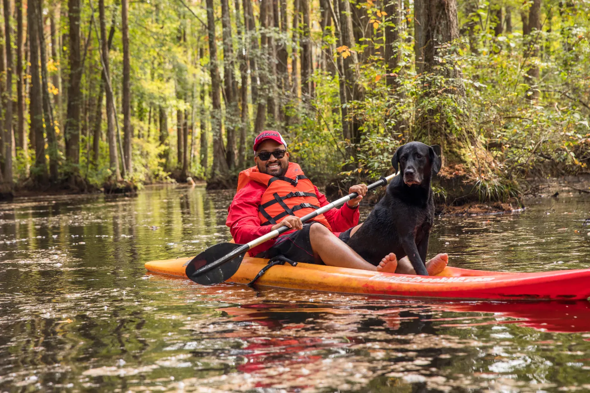 Man kayaking with his dog on a calm water trail in Wake County forest